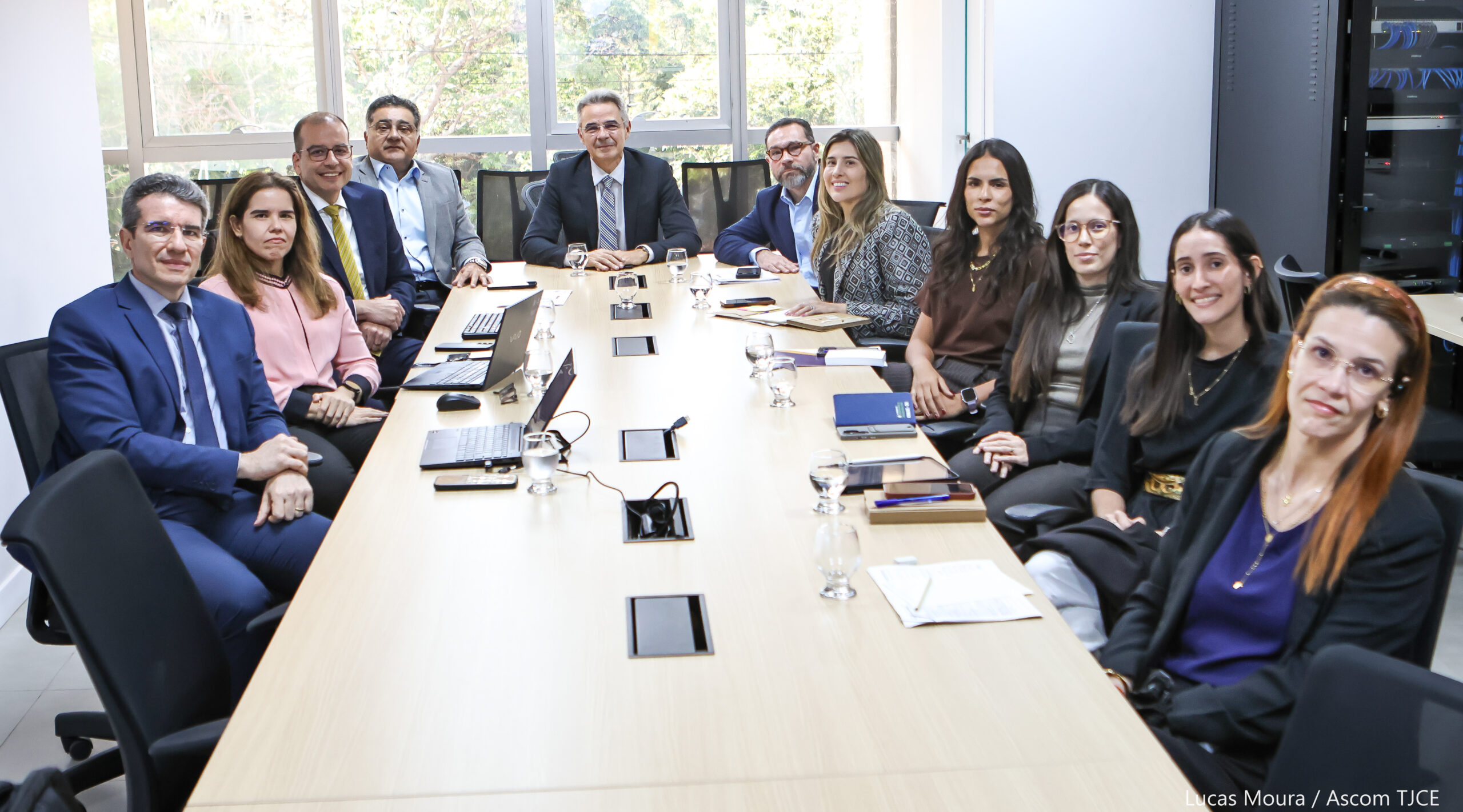 Fotografia de pessoas em torno de uma mesa de reunião, olhando para a câmera.