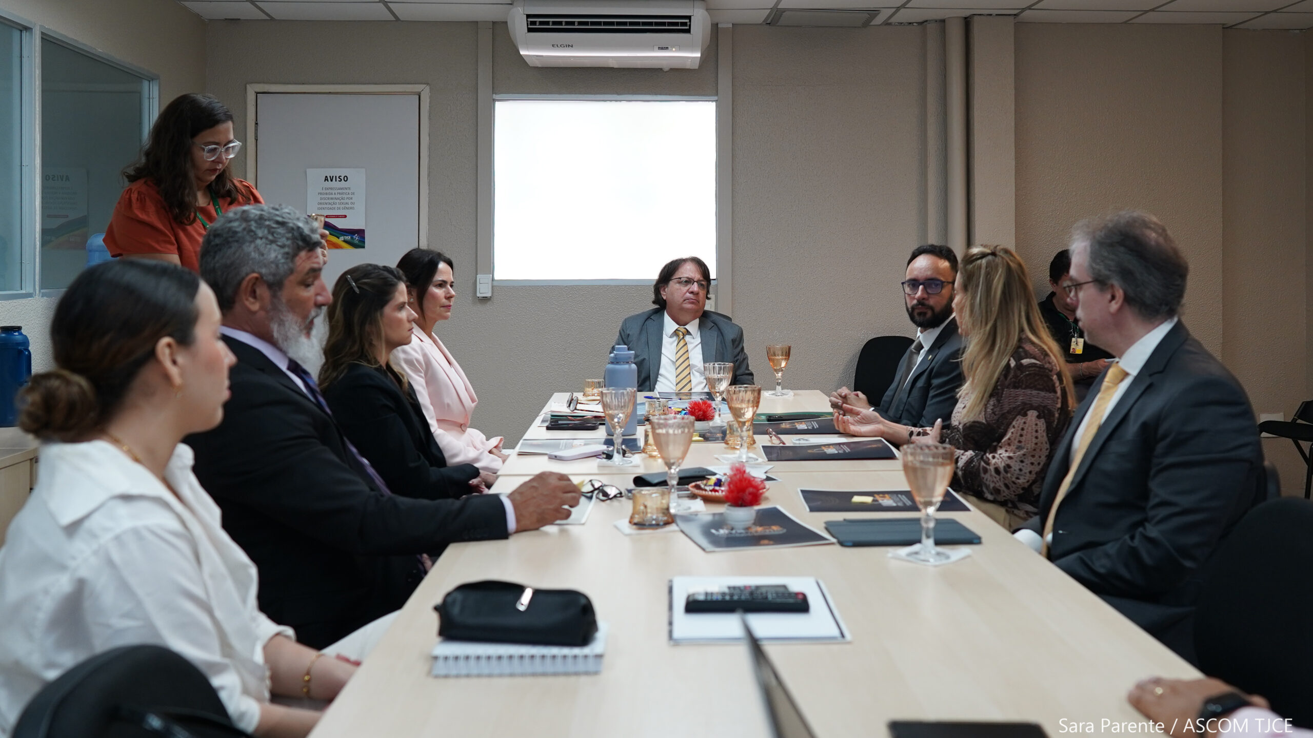 Fotografia de grupo de pessoas sentadas em uma mesa de reunião