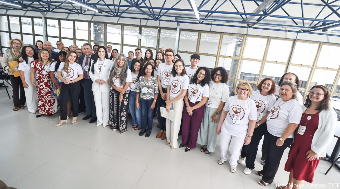 Um grande grupo de pessoas, posando para foto, ao final do evento. Elas estão perfilhadas, sorrindo, em pé, em amplo espaço aberto